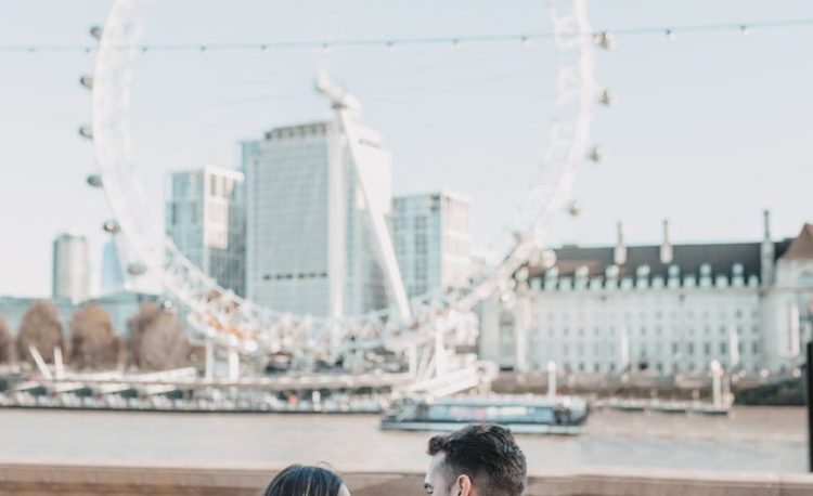 couple sitting on a bench with a view on london eye