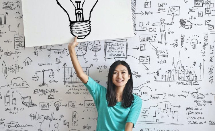 woman draw a light bulb in white board
