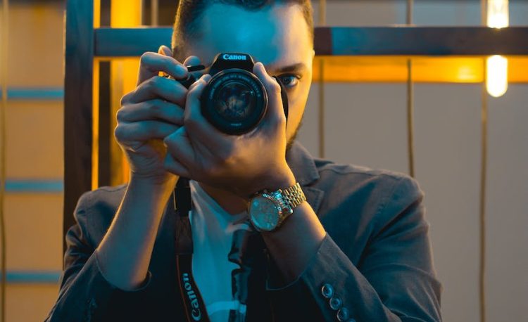 man in black suit holding canon dslr camera