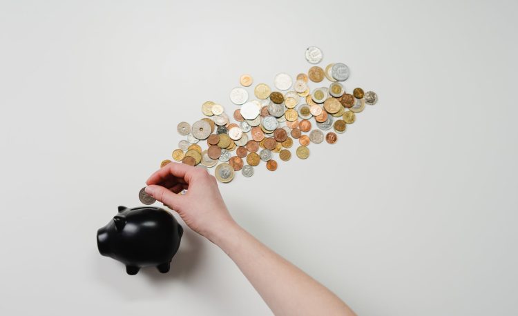 person putting coin in a piggy bank