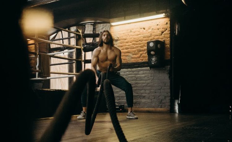 man in black pants and black tank top standing on brown wooden floor