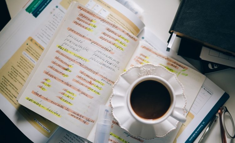a cup of black coffee on a notebook with notes of foreign language with translation