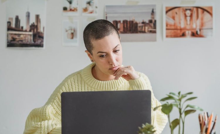 pensive woman working on laptop in light room