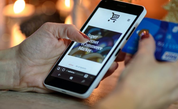 person using black and white smartphone and holding blue card