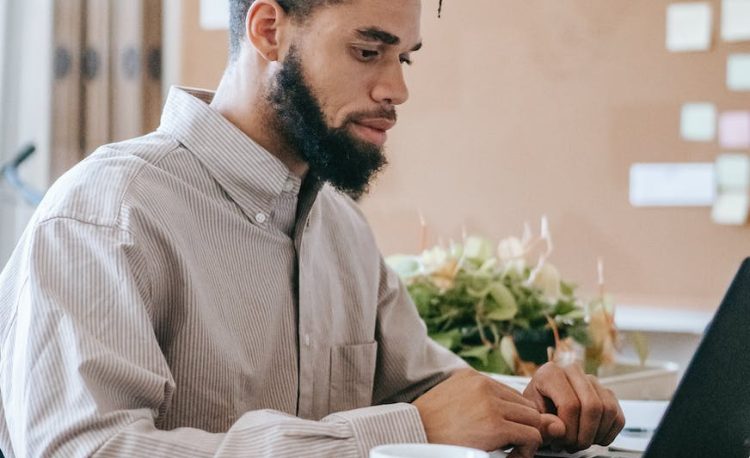 man in dress shirt sitting at the table using laptop computer