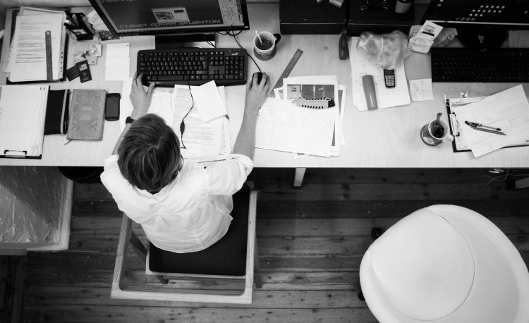 black and gray photo of person in front of computer monitor