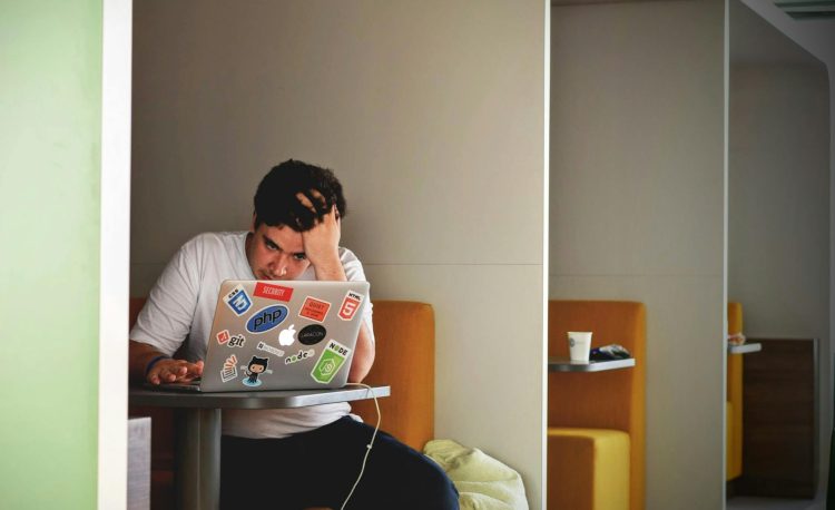 man in white shirt using macbook pro