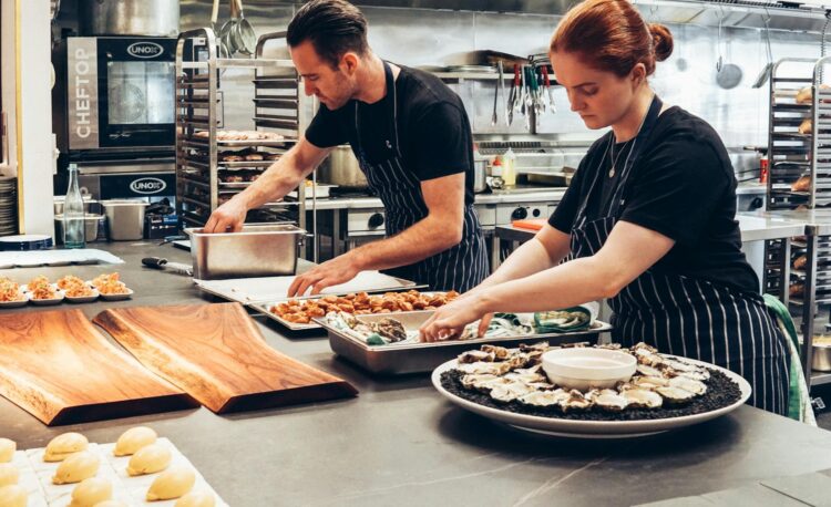 man and woman wearing black and white striped aprons cooking